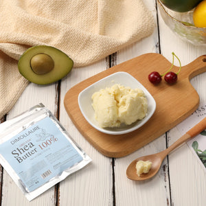 Shea butter on a wooden board with an avocado, cherry, and a package of Dimollaure Shea Butter 100%.