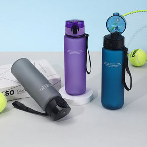 Three water bottles in gray, purple, and blue on a light blue background with tennis balls.