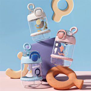 Set of baby bottles with colorful caps and teething rings on a pastel background