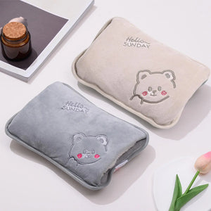 Two hot water bottles with bear designs and 'Hello Sunday' text on a light surface.