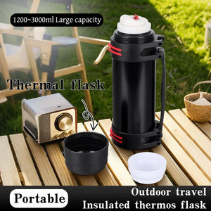 Black thermal flask with accessories on a wooden table outdoors
