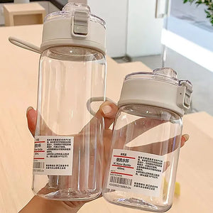 Two clear water bottles with white lids held by a hand on a light surface.