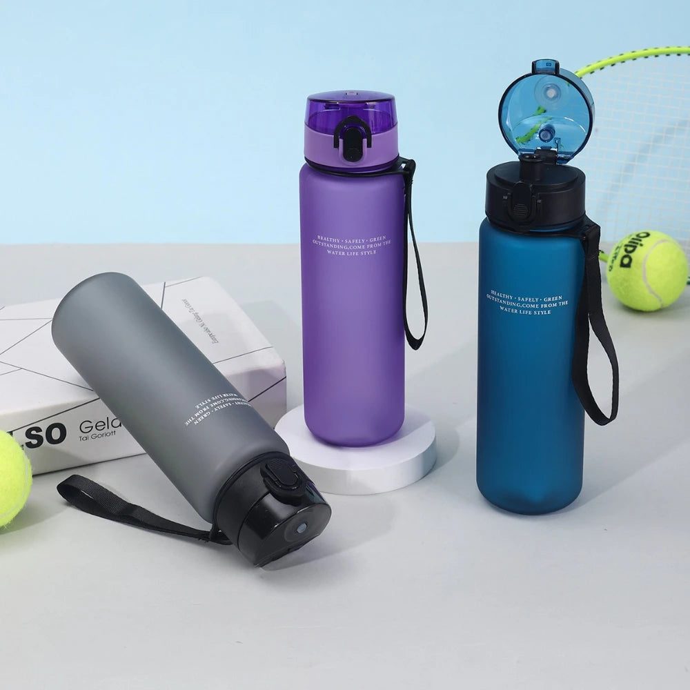Three water bottles in gray, purple, and blue on a light blue background with tennis balls.