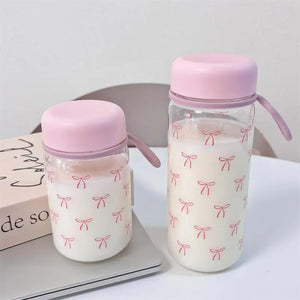 Two pink-lidded water bottles with bow pattern on a white surface