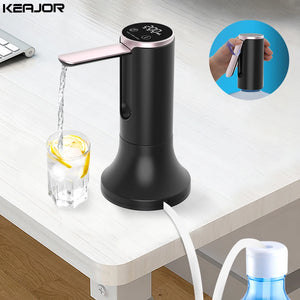 Black electric water pump on a desk with a glass of water and lemon, and a close-up of a hand holding a black mug.
