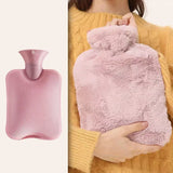 Pink hot water bottle with fuzzy cover held by a person wearing a yellow sweater.